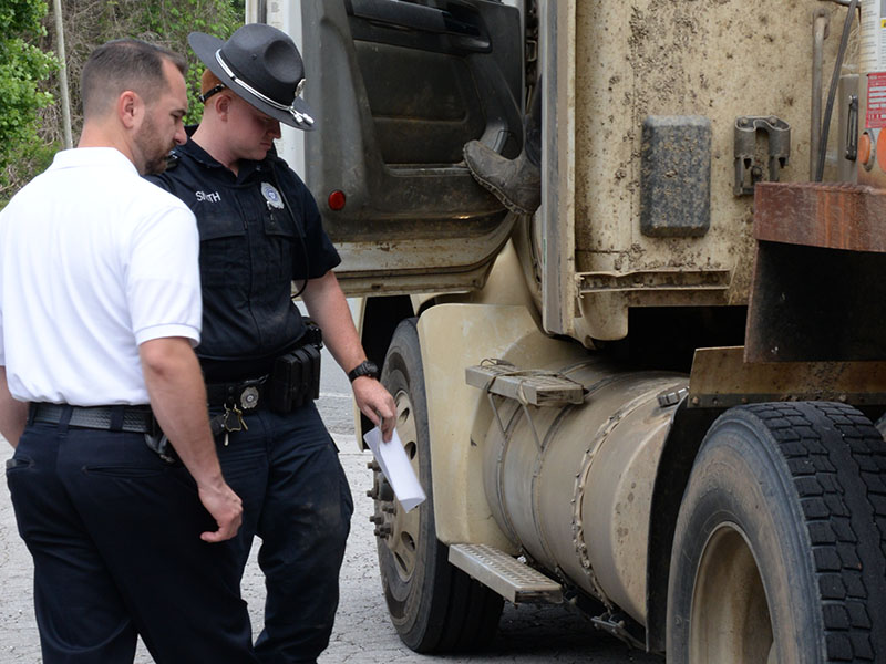 McCaysville Police Chief Michael Earley, lefrt, and Officer Hayden Smith of the Motor Carrier Compliance Division inspect an Atomic Transport 18-wheeler after it was stopped last week.