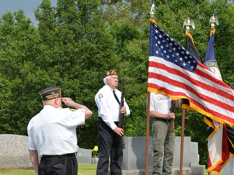 Gerald “Chief Mac” McMillian salutes as Ron Wallace and other members of the North Georgia Honor Guard prepare for a rifle salute at Crestlawn Cemetery.