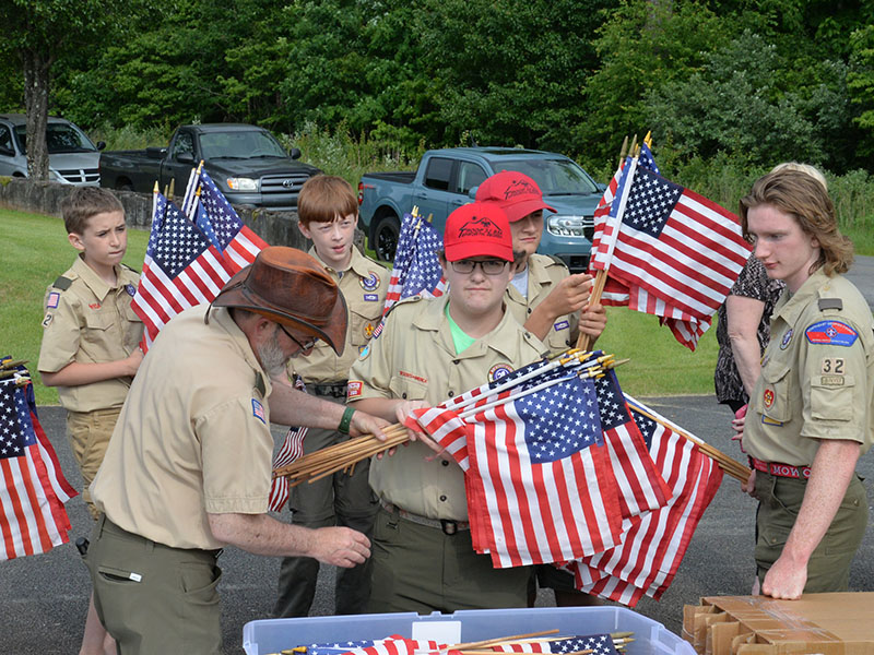 Scoutmaster David Lewis passes out United States flags to be placed on the graves of veterans at Crestlawn Cemetery to, from left, Troop 32 boy Scouts Stephen Young, Dakota Davis, Clay Dillard, Roy Green, Maddix Trantham, and Matthew Monroe. Placing the flags at the cemetery has long been an annual project of Troop 32.