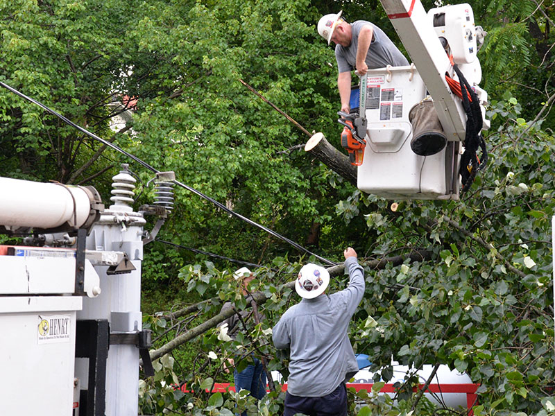 Wesley Jones, in bucket, passes a chain saw to Travis Sisson after a tree is cut away from the Pick Quick convenience store in McCaysville.