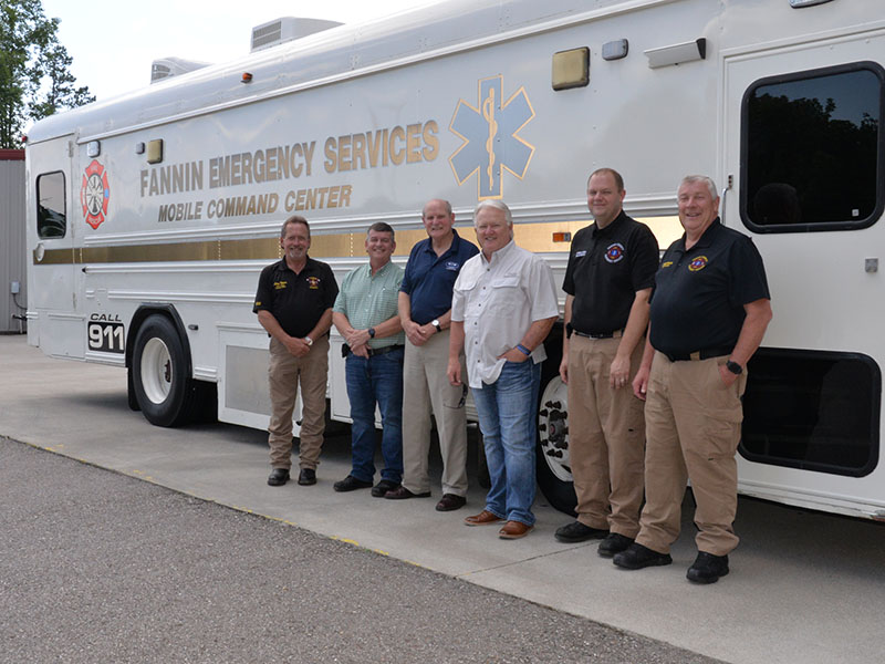 Fannin County officials unveiled the Emergency Management Agency’s (EMA) new Mobile Command Center last week. Shown in front of the large bus that is capable of operating the entire 911 communications center are, from left, Fire Chief Larry Thomas, Commission Chairman Jamie Hensley, Post 2 Commissioner Glenn Patterson, Post 1 Commissioner Johnny Scearce, Deputy EMA Director Patrick Cooke and EMA Director Robert Graham.