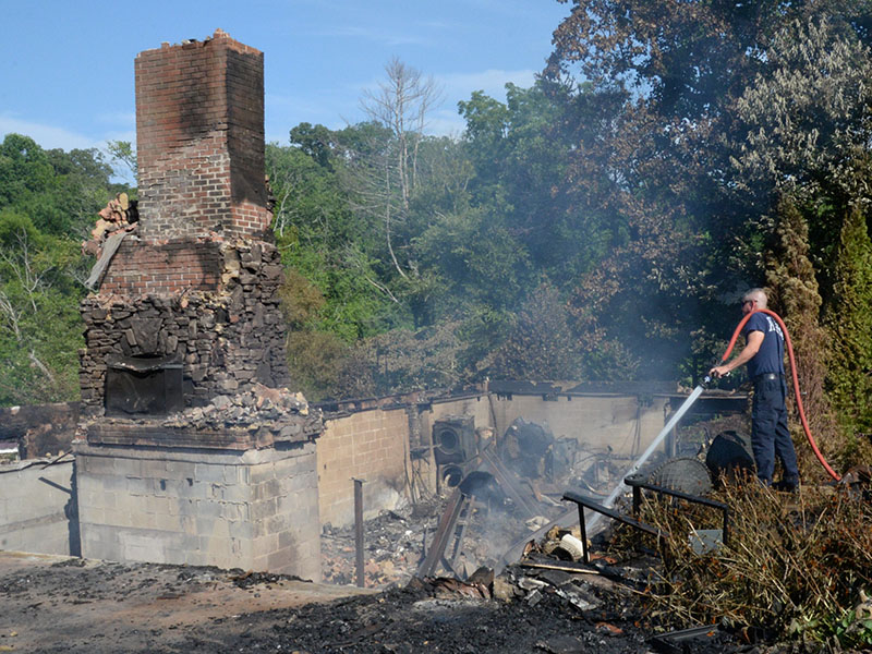 Fannin County Firefighter Brad Beaver waters down one of the smoldering spots Thursday morning that was left by the Wednesday fire. Firefighters returned to the location every two hours after the fire was extinguished to make sure everything was under control and protect nearby homes.