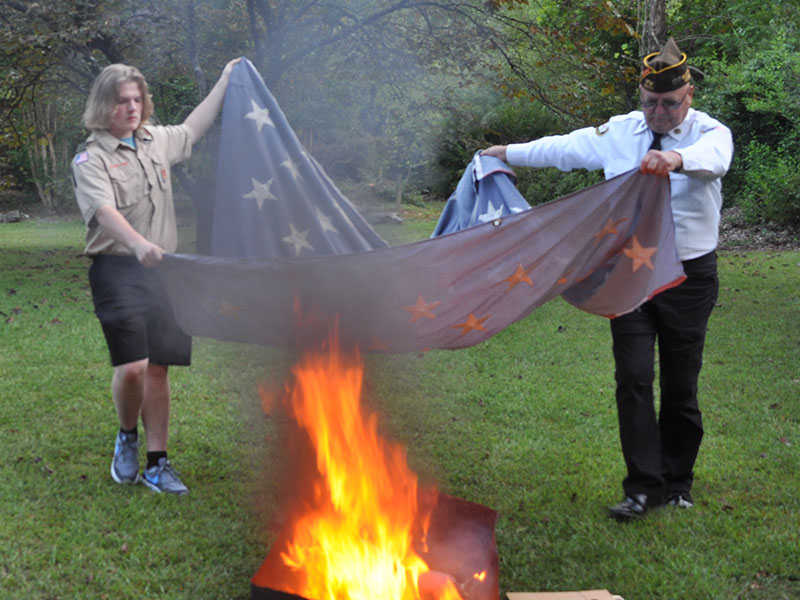  Soren Jolly, left, and North Georgia Honor Guard member Richard Crosley work together to place the canton of a flag in the fire.