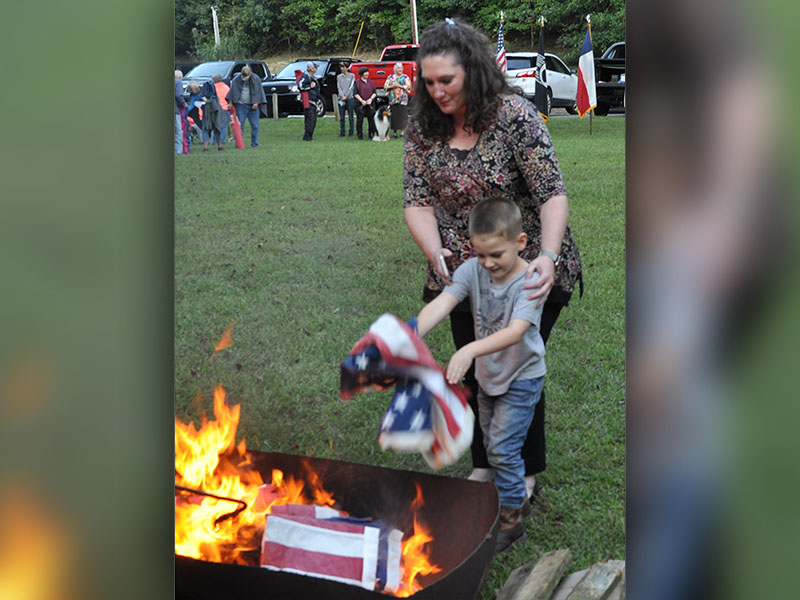 Cub Scout mom Jessica Threet helps her younger son, Aiden Threet, retire a flag.