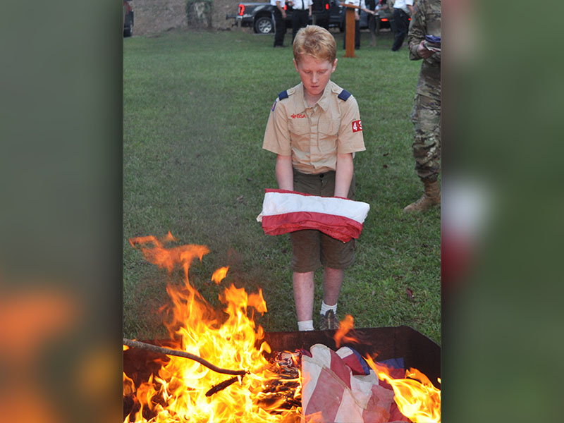 Troop 432 scout Ethan Threet prepares to properly retire a United States flag.