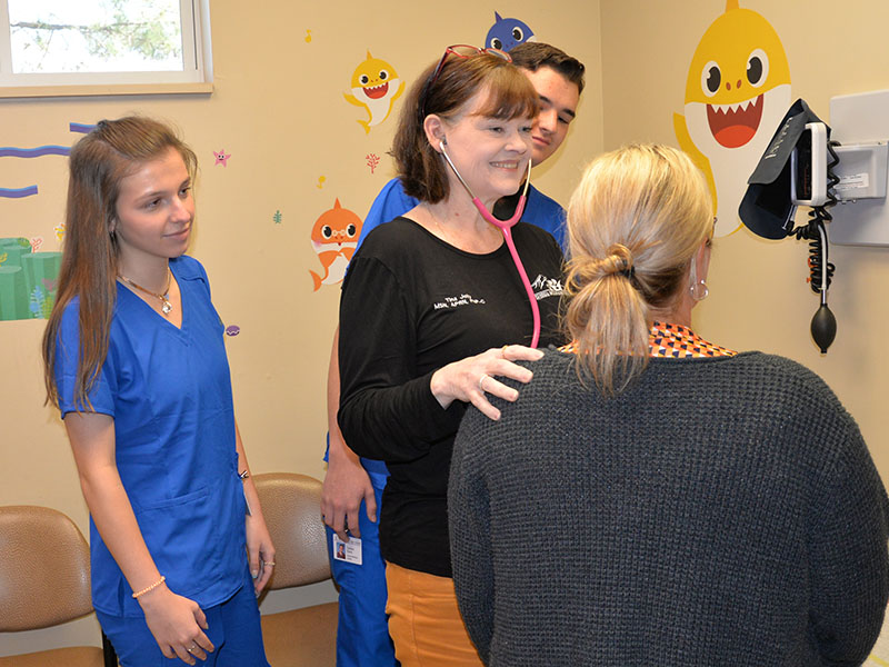 Blair Deal, left, and Trent Davis, obscured, watch as Tina Jolly of Georgia Mountains Health shows them the proper procedure on preliminary care for example patient Theresa Starnes.
