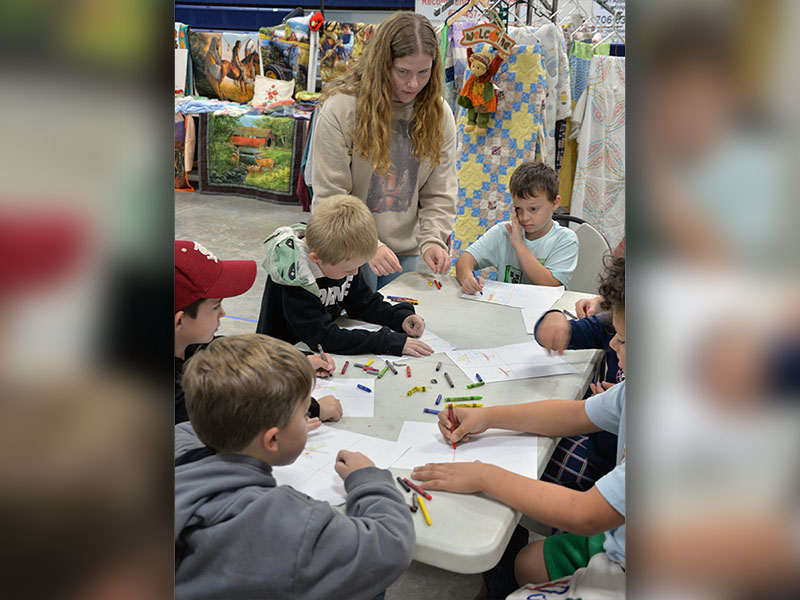 Fannin County High School FFA member Nichole Pulliam, standing, helps first graders Brayden Sinyard, Liam Gibson, Kanoa Garland, Conner McElwaney, and Anson Fortner participate in Apple Day activities.