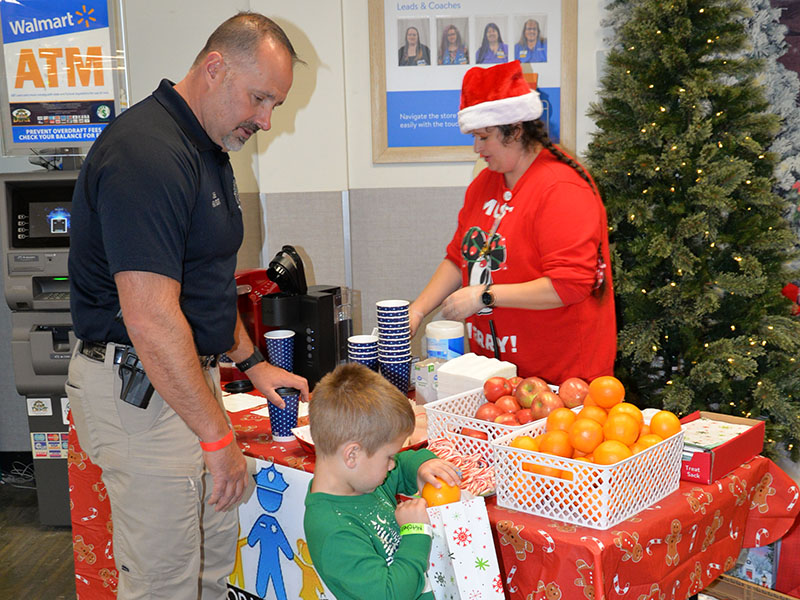 Blue Ridge Police Chief Robbie Stuart helped Mitchell Walker gather a few treats provided by the Blue Ridge Walmart for Shop With A  Cop.