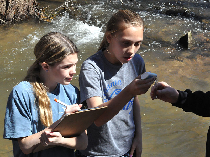 It is important to check the PH level of the water to ensure the trout survive in their new environment. Students, left, Elin Thoresen and Elizabeth Evans collected some of the water from the stream with STEM Teacher, Tori Arp and used a device to check it’s PH.