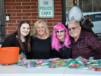 Kaylee Robertson, from left, Judy Earley, Madison Earley and City of McCaysville Mayor Thomas Seabolt smile while passing out candy in front of the McCaysville Police Department Saturday, October 31.