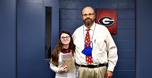 Fannin County High School student Emma Pittman and Fannin County Middle School Assistant Principal Mark Young display the Untold Stories book produced at the middle school by the Ignite Grant Board of Directors and dedicated to the veterans of Fannin County.