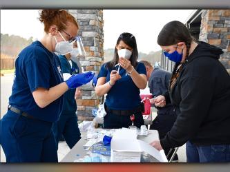 Fannin County EMA/Fire employees Trista Chancey, Tracy Padgett and Becky Huffman, shown from left, prep vaccines for school system employees.