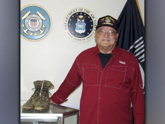 U.S. Air Force veteran Richard Crosley stands beside a pair boots he wore during his service.