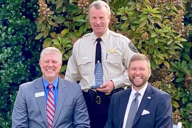 Fannin County Sheriff Dane Kirby, standing, was presented the Fannin County School System’s Pioneer in Education award by Pioneer RESA Executive Director Justin Old, seated left, and Fannin County School Superintendent Dr. Michael Gwatney.