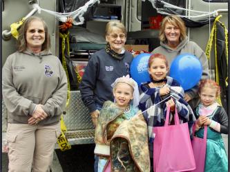 Despite a rainy evening, trick or treaters flocked to Blue Ridge’s Halloween Safe Zone Saturday, October 30. Shown are, from left, front row, Zoey, Chloe and Macy Lee; and back row, Fannin County Coroner Becky Callihan, Deputy Coroner Felicia Folds and Deputy Coroner Rebecca Hughson.