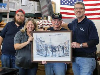 Habitat for Humanity of Fannin & Gilmer Counties’ ReStore Manager Jeanett McTaggart  hands off a World War II unit painting to veteran Rod McIntyre with the Fannin County Veterans Museum. Around them are, from left, Ryan Maston and Salvatore Maniscalco.