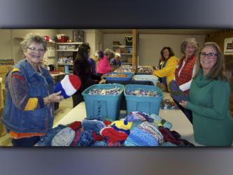 Kim King, left, and Jane Meyer worked together to knit hats to go in the Snack in a Backpack bags for children before Christmas.
