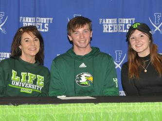 Rebels soccer player Payton Roath smiles after signing to play soccer for Life University. He is accompanied by his mother Tiffany Roath, left, and his sister Cassi Roath.