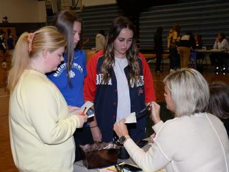 Lyla Webb, Bridgette Allen and Cheyenne Beavers get help from Stacy Lewis of Mountain Valley Community Bank during Reality Day at Fannin County High School last week.