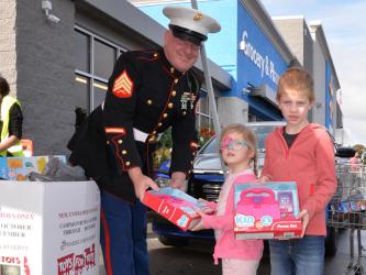 Eleanor and Theodore Parsons-Cohrs dropped off donations at Toys for Tots’ Stuff the Truck at the Blue Ridge Walmart parking lot Saturday morning. Accepting the donations is Marine Corps Sergeant Brent Ware. Toys for Tots is still taking requests for help at the Fannin County Family Connection building through December 14 and collecting toys through the same day. Distribution will be at Family Connection Friday and Saturday, December 16 and 17, from 10 a.m. until 6 p.m. each day.