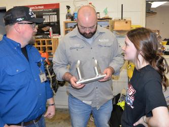 Fannin County High School welding instructor Terry Flowers, left, and advisory board member Devin Johnson, admire the work of student Emmaline Cochran, right.