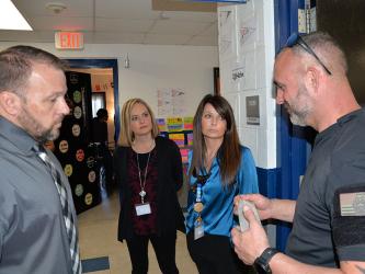 Corporal David Ridings, right, with the Gilmer County Sheriff’s Office, describes the bait used to train drug detecting dogs to, from left, Fannin County High School Principal Dr. Scott Ramsey and assistant principals Heather Collis and Mandy Housley. After a thorough search of FCHS last week, the five dogs used were put through a training exercise in one of the classrooms.