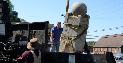 Lee Dillard operates the crane moving the Veterans Monument as Albert Queen helps guide it into position.