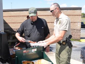 School Resource Officers and Fannin County deputy sheriffs Jim Burrell, left, and Lieutenant Darvin Couch were busy getting hamburgers and hotdogs ready for the participants in Saturday’s Riding the Ridge to benefit Shop With a Cop.