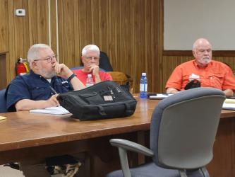 Buddy Haynes, from left, Ricky Brooks and David Darden, members of the Polk County Industrial and Economic Development Board, listen as Polk County Commission Chairman John Pippenger asks for Haynes to be removed from the board.