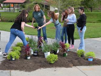 Ginger Montgomery, center, helps Sadie Deal, left, and  Serenity Presley design their flower bed.